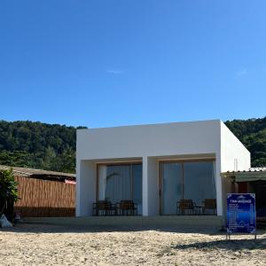 a white building on the beach with a sign in front at lovelytheroom in Ko Lanta