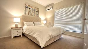 a bedroom with a large white bed and a window at Perfect North Brisbane Retreat 4 bed in Griffin