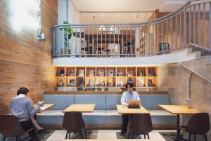 two people sitting at tables in a restaurant with their laptops at Hotel Relief Kokura Annex in Kitakyushu