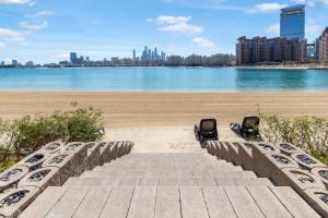 einen Strand mit zwei Stühlen und einem Sandstrand in der Unterkunft FAM Living - Palm Jumeirah - Beach Villas with Private Pool in Dubai