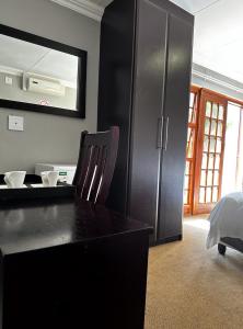 a bedroom with a black dresser and a mirror at The Hempel Guesthouse in Mokopane