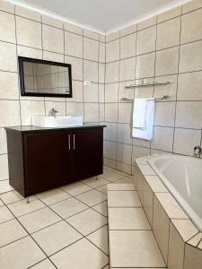 W łazience znajduje się umywalka i wanna. w obiekcie The Hempel Guesthouse w mieście Mokopane