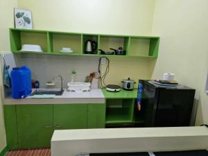 a kitchen with green cabinets and a black refrigerator at Waray WaRaE Haven in Tacloban