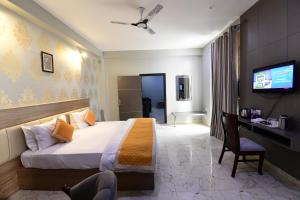 a hotel room with a bed and a desk and a tv at Hotel Jataka Inn in Bodh Gaya
