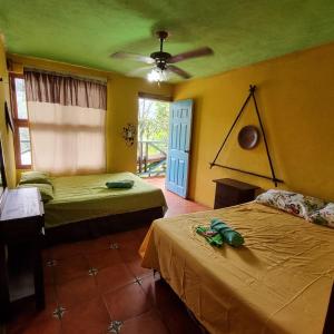 Cette chambre comprend deux lits et un ventilateur de plafond. dans l'établissement CARIBbEAN Paradise Hotel, à Lanquín