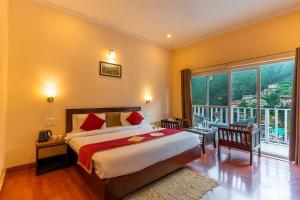 een slaapkamer met een groot bed en een groot raam bij Hotel Vista Bhowali, Nainital - Vegetarian in Bhowāli