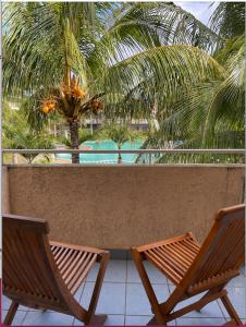 2 Stühle und ein Tisch auf einem Balkon mit Palmen in der Unterkunft Your west coast getaway in Flic-en-Flac