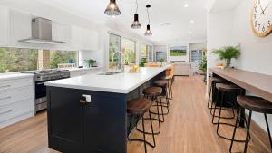 a kitchen with a large island with bar stools at Forest Brae in Bundanoon
