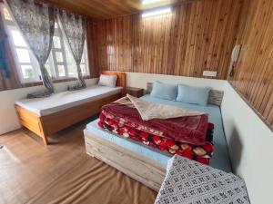 two beds in a room with wooden walls and windows at Boho Homestay, Rangbhang in Darjeeling