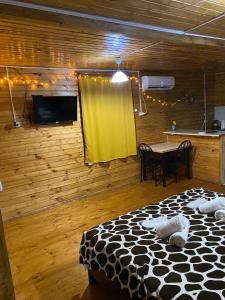 a room with a bed and a table with a yellow curtain at Wooden Cottages - Mtskheta in Mtskheta