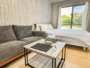 ein Wohnzimmer mit einem Sofa und einem Bett in der Unterkunft 与那国むんぶステイ空港前 in Sonai
