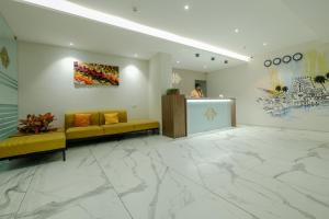 un vestíbulo con sofás amarillos y pinturas en la pared en The HEARTLAND Hotel, en Trivandrum