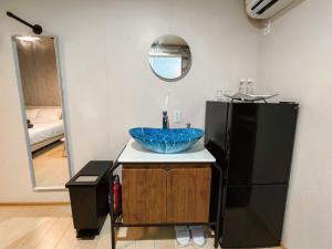 ein Bad mit einem Waschbecken und einem schwarzen Kühlschrank in der Unterkunft 与那国むんぶステイ空港前 in Sonai