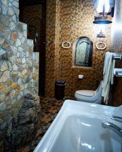 a bathroom with a tub and a toilet and a sink at Fort Mughaibar Resort in Hatta