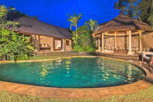 a swimming pool in front of a house with a gazebo at Villa Kubu Seminyak in Seminyak