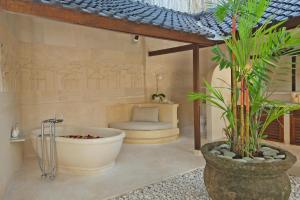 a bathroom with a tub and a chair and a plant at Villa Kubu Seminyak in Seminyak