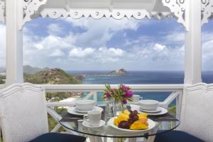 a table with a plate of fruit on a balcony with the ocean at Brise De Mer - Villa with captivating views of the Caribbean Sea villa in Cap Estate