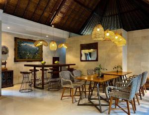 a restaurant with wooden tables and chairs and chandeliers at Villa Puriartha Ubud - CHSE Certified in Ubud