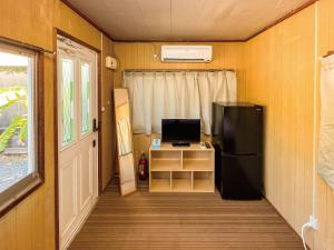Habitación pequeña con nevera y TV. en 与那国むんぶステイ祖納, en Sonai