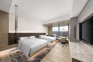 two beds in a room with a tv and a bedroom at Renaissance Shenzhen Bay Hotel in Shenzhen