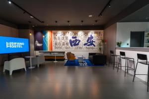 Sifang Space Hostel Xi'an - Xi'an KEJIDAXUE metro Line4 في شيان: غرفة بها تلفزيون وجدار مع علامة