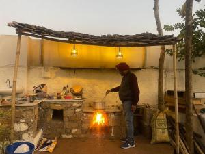 Un uomo che cucina sopra un fuoco in una cucina di Auspicious villa a Udaipur