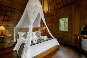 a bedroom with a bed with a mosquito net at Anandari Ubud Villa in Ubud