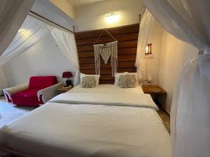 um quarto com uma grande cama branca e um sofá vermelho em Auspicious villa em Udaipur