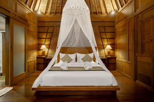 a bedroom with a bed with a mosquito net at Anandari Ubud Villa in Ubud