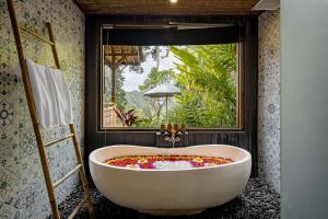 uma banheira na casa de banho com uma janela em Anandari Ubud Villa em Ubud