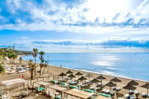 plaża z parasolami i ludzie w wodzie w obiekcie Mijas Costa - Beachside Apartment-B w mieście Mijas Costa