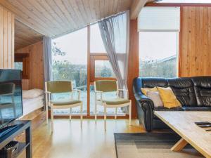a living room with a black leather couch and chairs at Secluded Retreat with Sauna - By Traum Ferienwohnungen in Sønderby