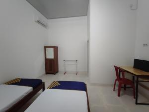 a room with two beds and a table and a desk at SPOT ON 93350 Alnasya Syariah in Palembang