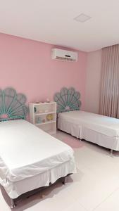 two beds in a room with pink walls at A casa Pipa in Pipa