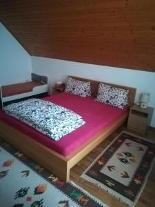 a bedroom with a large bed with purple sheets and pillows at Apartmán Nina in Oravská Polhora