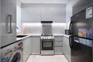a white kitchen with a stove and a dishwasher at Homesgetaway - Ultraluxury 1BR in Binghatti Creek - Al Jaddaf in Dubai