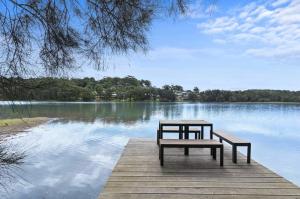 two benches sitting on a dock near a lake at Surf Lodge Avoca Beach Waterfront to Avoca Lake in Avoca Beach