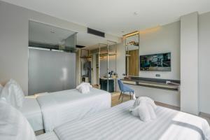 a hotel room with two beds and a desk at Rak Elegant Hotel Patong in Patong Beach