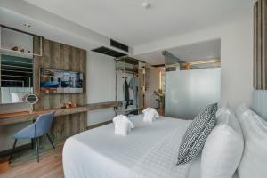a bedroom with a large white bed and a blue chair at Rak Elegant Hotel Patong in Patong Beach