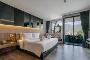 a bedroom with a large bed and a balcony at Rak Elegant Hotel Patong in Patong Beach