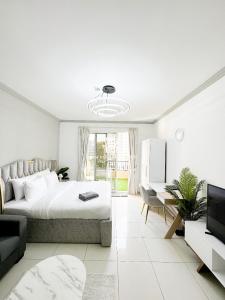 - une chambre blanche avec un lit et un salon dans l'établissement Studio at Spring Oasis Dubai Silicon Oasis By ANW Vacation Homes, à Dubaï