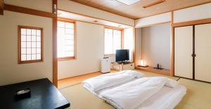 a large room with a bed and a television at JR Hotel Clement Uwajima in Uwajima