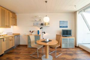 eine Küche mit einem Tisch mit Stühlen und einem TV in der Unterkunft Ferienwohnung Hafen & Strand in Schilksee