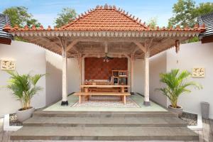 a wooden pergola with a picnic table on a patio at Vivara Bali Private Pool Villas & Spa Retreat in Jimbaran