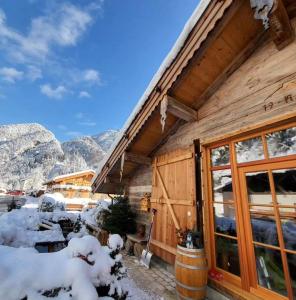 ein Blockhaus mit Schnee seitlich in der Unterkunft Nickis Bergcamp in Schneizlreuth