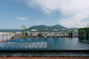a large swimming pool with chairs and umbrellas at Rak Elegant Hotel Patong - SHA Extra Plus in Patong Beach