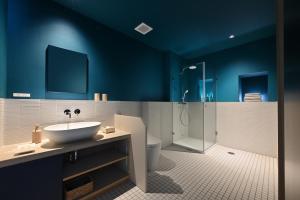 ein Badezimmer mit blauen Wänden, einem Waschbecken und einer Dusche in der Unterkunft ROOM design hotel in Nanao