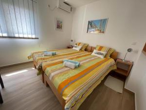 1 Schlafzimmer mit 2 Betten und gestreifter Bettwäsche in der Unterkunft Acacia Hill Apartment C01 in Ðenovići