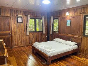 a bedroom with a bed with wooden walls and windows at คุ้งน้ำ รีสอร์ท นครนายก in Ban Khao Kariang (1)