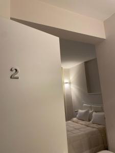 duas camas num quarto branco com o número dois na parede em Midtown Salerno em Salerno